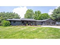 Charming one story home featuring a covered front porch, mature trees, and an attached two-car garage at 11423 Atlantic Rd, Fortville, IN 46040