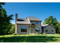 Two-story home with a stone chimney, green lawn, tidy landscaping, and a well-manicured lawn under a bright blue sky at 11875 W 700 S, Columbus, IN 47201