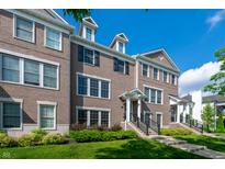Charming townhome featuring a brick facade, front lawn, and welcoming front porch with decorative columns at 1972 Rhettsbury St, Carmel, IN 46032