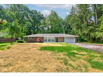 Charming brick ranch home featuring an attached garage and a tree-lined front yard at 3339 Devereaux Dr, Indianapolis, IN 46228