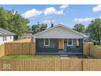 Charming home featuring a fenced yard, gray brick porch, and a bright yellow front door at 3716 W 16Th St, Indianapolis, IN 46222