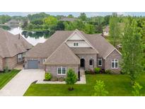 Beautiful single-Gathering home with gray brick exterior, manicured lawn, and large backyard with lake view at 4359 Prairie Falcon Dr, Zionsville, IN 46077