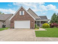 Charming brick home with a two-car garage, a cozy front porch, and well-manicured landscaping at 4399 Summerhaven Dr, New Palestine, IN 46163