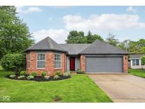 Charming brick home featuring an attached garage and a well-manicured lawn, with a red front door at 7061 Woodgate Cir, Fishers, IN 46038