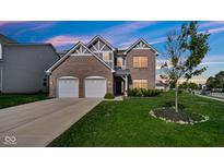 Charming two-story brick home featuring a two-car garage and beautifully landscaped front yard at 9717 Chuckwalla Pl, Fishers, IN 46040