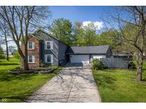 Charming home featuring a long driveway and a two-car garage, framed by mature trees and a well-maintained lawn at 1052 Barley Cir, Carmel, IN 46032