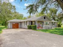 Charming single story home with gray siding, red rocking chairs, lovely front yard and detached garage at 12508 N Jackley Rd, Elwood, IN 46036