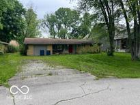 Modest single-story home with a red front door, attached garage and an unkempt front yard at 130 Napanee Dr, Carmel, IN 46032