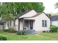 Charming single-story home with tan siding, a cozy front porch, and green foliage at 1331 N Berwick Ave, Indianapolis, IN 46222