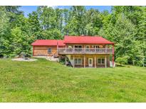 Beautiful log home with a red metal roof and a wraparound porch, surrounded by lush greenery at 2780 W Grizzly Trl, Martinsville, IN 46151
