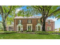 Charming brick two-story home with a manicured lawn, mature trees, and beautiful copper bay windows at 5165 E Pleasant Run Pkwy S Dr, Indianapolis, IN 46219