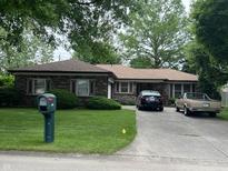 Charming brick ranch-style home with a lush front lawn, mature trees, and a private driveway at 539 Queenswood Dr, Indianapolis, IN 46217