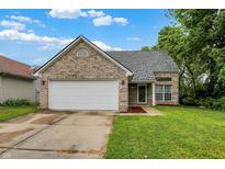 Charming single-story brick home with an attached two-car garage, green lawn, and a cloudy blue sky at 6010 Lakeside Manor Ave, Indianapolis, IN 46254