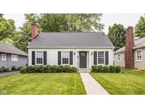 Charming home featuring a manicured lawn, a classic brick chimney and shutters on the windows at 6040 Crittenden Ave, Indianapolis, IN 46220