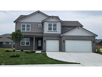 Charming two-story home featuring a two-car garage, gray brick, lush lawn and manicured landscaping at 6049 Madera Dr, Whitestown, IN 46075