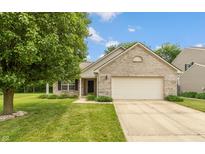 Charming brick home featuring an attached two-car garage and a well-maintained lawn and mature shade tree at 6369 Clary Ln, Greenwood, IN 46143
