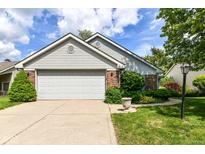 Charming home featuring a two-car garage, brick accents and well manicured landscaping at 8713 Champions Dr, Indianapolis, IN 46256