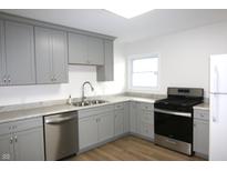 Kitchen featuring gray cabinets, stainless steel appliances, granite countertops, and wood look floors at 1021 Harney Dr, Lebanon, IN 46052