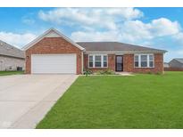 Charming brick home featuring an attached two car garage, well-maintained lawn and partial landscaping at 107 Elliott Ave, Trafalgar, IN 46181