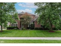 Beautiful brick home with a manicured lawn and mature trees providing shade and curb appeal at 13693 Cunningham Dr, Carmel, IN 46074