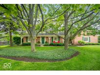 Beautiful brick home with mature trees, a green lawn, and a cozy front porch at 3295 Allison Ct, Carmel, IN 46033