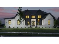 Stunning two-story home featuring white brick and dark vertical siding at dusk at 3713 Cherwell Dr, Zionsville, IN 46077