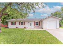 Charming home featuring a one-car garage, red shutters, and a well-maintained lawn at 5602 Northport Dr, Indianapolis, IN 46221
