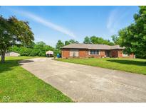 Single story brick home featuring an extra long driveway and well-maintained landscaping at 564 Penright Ct, Indianapolis, IN 46217