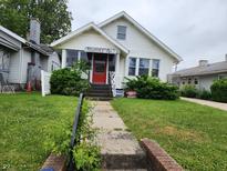 Charming two-story home with a well-manicured lawn, sidewalk, and decorative shrubs at 621 E 31St St, Anderson, IN 46016