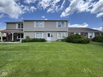 Charming two-story home with a well-manicured lawn and beautiful landscaping on a sunny day at 7445 Melanie Ln, Indianapolis, IN 46217