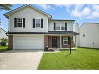 Charming two-story home featuring a well-maintained lawn, attached garage, and inviting front entrance at 7549 Stockard St, Indianapolis, IN 46239