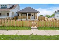 Charming home featuring a cozy front porch and a well-maintained lawn with a decorative wooden fence at 2909 E Michigan St, Indianapolis, IN 46201