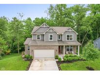 Charming two-story home featuring a brick facade, attached garage, and covered front porch with seating area at 527 Macintosh Ln, Danville, IN 46122