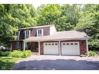 Charming brick home with a two-car garage and a well-manicured lawn surrounded by lush trees at 7115 Fremont Ct, Indianapolis, IN 46256