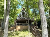 A-frame home with a wraparound deck surrounded by beautiful trees and lush foliage at 7207 Grouper Dr, Nineveh, IN 46164