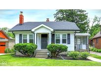 Charming home featuring manicured lawn, mature shrubbery, and a cozy front porch entrance at 907 N Arlington Ave, Indianapolis, IN 46219