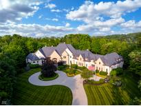 Stunning aerial view of a large luxury home with beautiful landscaping, a circular driveway, and mature trees at 11101 Hawthorn Rdg, Fishers, IN 46037