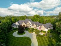 Stunning aerial view of a luxury home featuring manicured lawns, a circular driveway, and mature trees at 11101 Hawthorn Rdg, Fishers, IN 46037