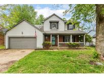 Charming two-story home with a covered porch, attached garage, and manicured lawn at 1113 Delray Dr, Indianapolis, IN 46241