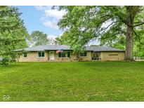 Sprawling brick ranch-style home features a large lawn, mature trees, and an American flag displayed in the front window at 1248 Hathaway Dr, Indianapolis, IN 46229