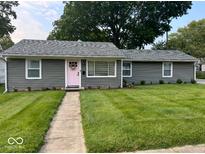 Charming single-story home featuring a well-manicured lawn and a delightful pink front door with wreath at 1398 Clinton St, Noblesville, IN 46060