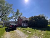 Charming red home with a white picket fence, a gravel driveway, and a well-maintained lawn at 2115 S I St, Elwood, IN 46036