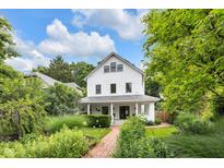 Charming white two-story home with a landscaped front yard and inviting brick walkway under a sunny, partly cloudy sky at 3215 N Pennsylvania St, Indianapolis, IN 46205