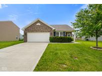 Charming brick home featuring an attached two-car garage and a well-maintained lawn with landscaping at 6415 Calabash Pl, Indianapolis, IN 46217