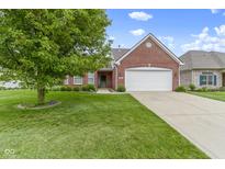 Well-maintained brick home with a manicured lawn, mature tree, and attached two-car garage at 7128 Willow Pond Dr, Noblesville, IN 46062