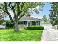 Charming single-story home with a well-maintained lawn, lush landscaping, and detached garage at 7725 E 52Nd St, Indianapolis, IN 46226