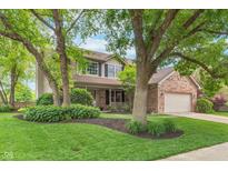 Charming two-story home with well-manicured lawn, mature trees, and brick accents at 10673 Misty Hollow Ln, Fishers, IN 46038