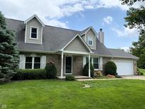 Charming brick home featuring dormer windows, well-manicured lawn and landscaping and a two-car garage at 1135 W Wildflower Ct, Mooresville, IN 46158