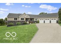 Charming single-story home with a three-car garage, stone accents and a lush lawn at 25050 State Road 213, Cicero, IN 46034
