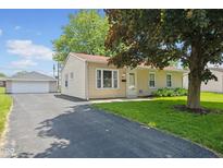 Charming single-story home with a well-manicured lawn, asphalt driveway, and detached garage at 3427 Donald Ave, Indianapolis, IN 46224
